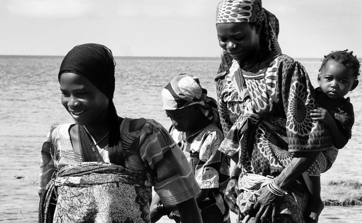 Local women and children walking by the sea on Vamizi Island.